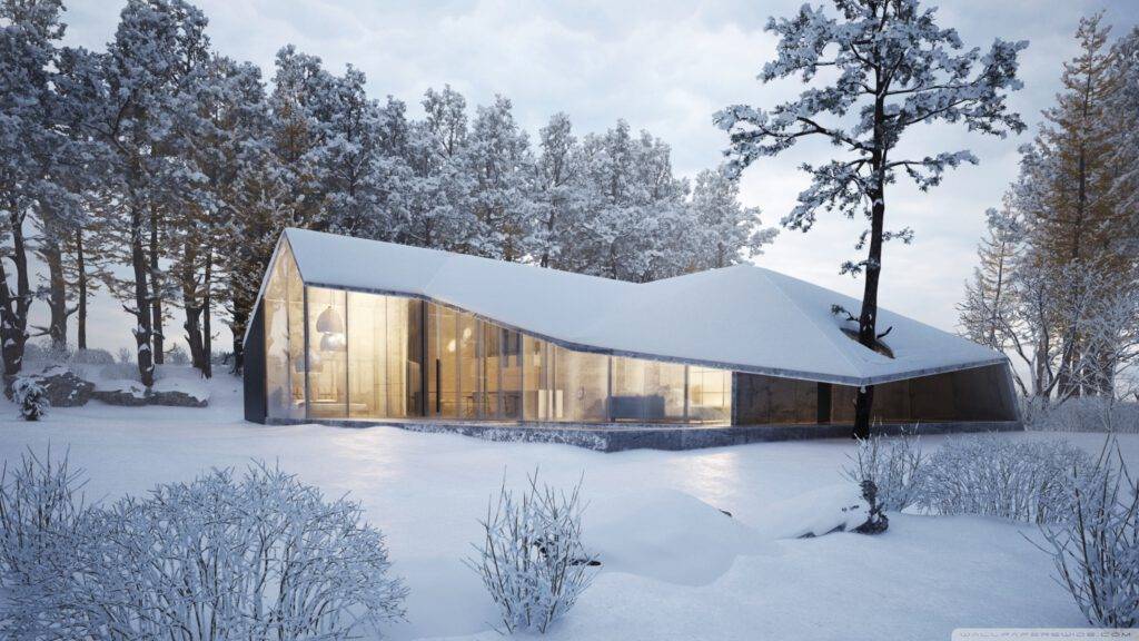 Modernes Haus mit großflächiger Verglasung eingebettet in eine schneebedeckte Waldlandschaft im Winter.